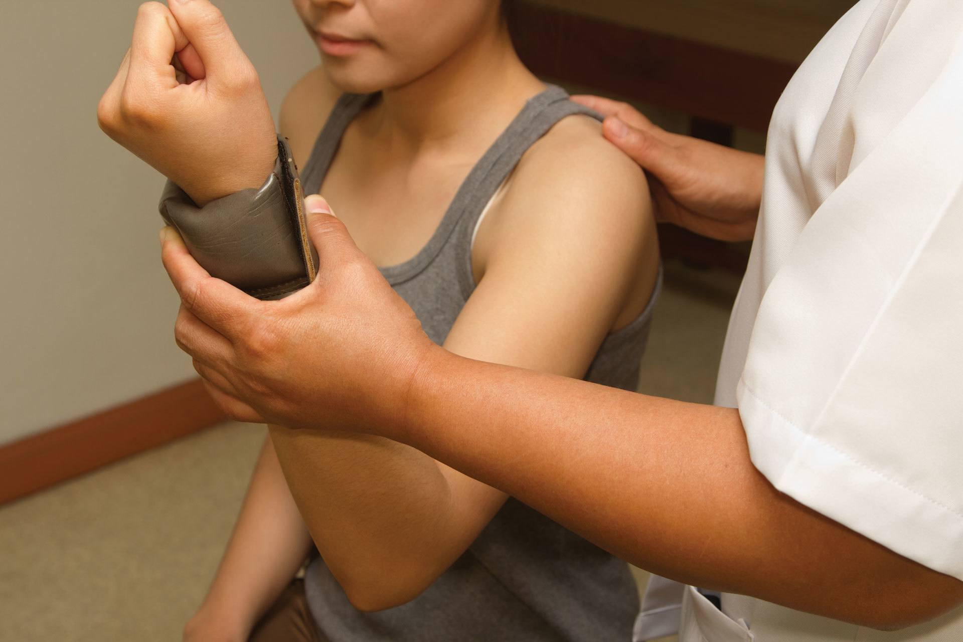 一名来自BGSU应用健康科学项目的学生协助一名手腕受伤的年轻病人进行检查.